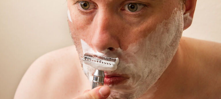 man shaving with safety razor